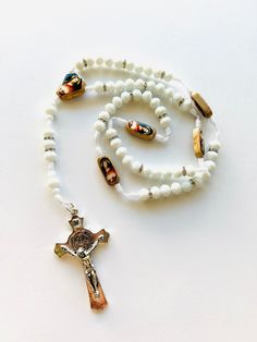 Rosario de 59 cuentas para rezo hecho a mano con cristal cortado Blanco perla e imagen del Sagrado Corazon de Jesus en tableta de madera color natural y finalizado con una cruz de San Benito de metal plateada. para hombre o mujer, o colgarse en el espejo retrovisor del carro para Bendicion y Proteccion en el manejo. material: cristal color BLANCO PERLA SOLIDO 10 mm tableta de madera color natural pequeña rectangular con imagen ambos lado como padre nuestro 2.50cm x1cm x 0.6cm crucero en forma de Virgin Mary Necklace, Gold Bead Bracelets, Gold Chain Necklace, Sacred Heart, Black Glass, Gold Beads, Real Gold, Rosary, Bead Charms