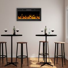 three bar stools in front of a fireplace with candles on the table and two wine glasses