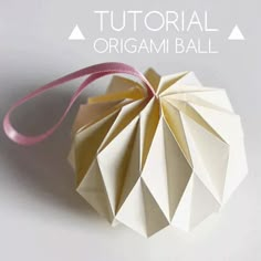 an origami ball hanging from a pink ribbon