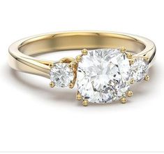 three stone engagement ring in yellow gold with two diamonds on each side and an oval cut diamond