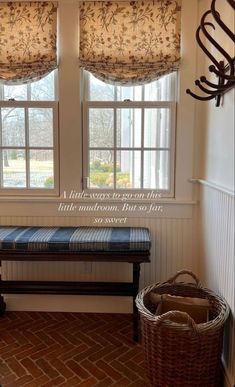 a bench sitting in the corner of a room next to two windows with valances on them