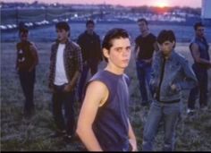 a group of young men standing next to each other in a field at sunset or dawn