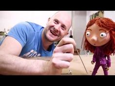 a man with red hair holding a knife next to a cartoon doll on the floor