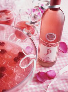 a glass bowl filled with ice and strawberries next to a bottle of pink wine