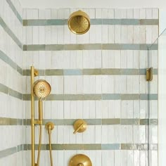 a bathroom with gold fixtures and white tiles on the walls, including a shower head