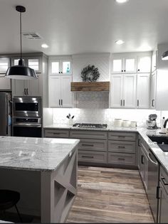 a large kitchen with white cabinets and wood flooring