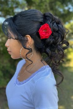 This captivating hairstyle showcases soft, flowing curls delicately swept to one side, crafting a romantic and feminine look befitting a quinceañera celebration. A vibrant red flower is nestled amidst the tresses, acting as a striking focal point that infuses a touch of traditional charm. Wispy strands tenderly frame the face, enhancing the - Click to see more of 34 Adorable and Unique Quinceañera Hairstyles to Try and follow us for more hairstyle ideas. // Photo Credit: Instagram @hairbyzue Up Do Hairstyles For Quinceanera, Charro Hairstyles, Mexican Updo Hairstyles, Mexican Hairstyles Short Hair, Quince Hair Updos, Mariachi Hairstyles, Quinceanera Hairstyles With Flowers, Short Hair Quinceanera Hairstyles, Mexican Wedding Hairstyles