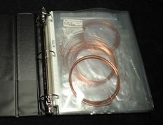 an open binder with two copper colored wires in it and a black bag on the floor