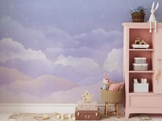 a child's room with pink furniture and clouds painted on the wall behind it