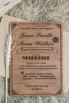 a wooden wedding card with a feather on it