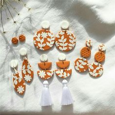 the orange and white earrings have tassels attached to them, with flowers on them