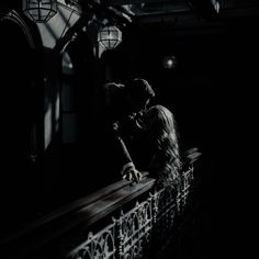 black and white photograph of a woman leaning on a railing in the dark with her head down