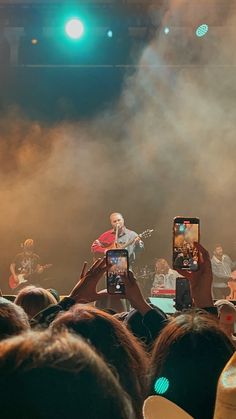 two people taking pictures with their cell phones while on stage at a music festival or concert