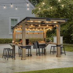 an outdoor patio with lights strung over the grill and bar area, surrounded by greenery