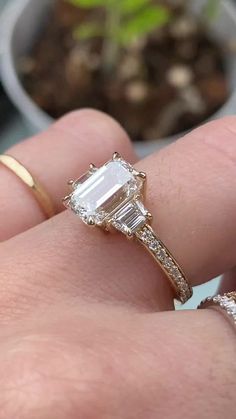 a close up of a person's hand holding an engagement ring