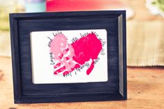 a picture frame with a handprinted heart on it sitting on top of a table