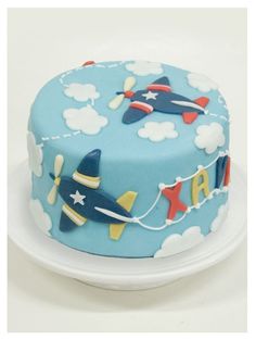 a blue cake with airplanes and clouds on it's icing is sitting on a white plate