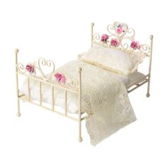 a white doll bed with pink roses on it