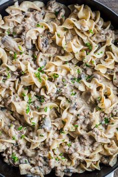 a skillet filled with pasta covered in meat and sauce, garnished with parsley