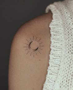 a woman's arm with a small sun and moon tattoo on the left shoulder