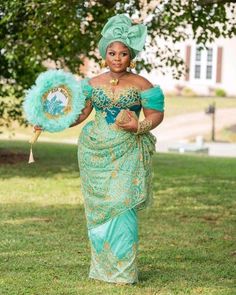 a woman in a green dress holding a fan and wearing an elaborate headdress