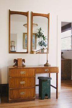 a wooden dresser sitting next to a mirror on top of a hard wood floor covered in furniture