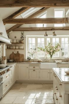 a white kitchen with lots of counter space and wooden beams on the ceiling above it