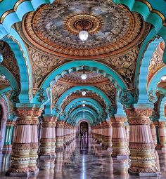 an ornately decorated hallway with columns and ceiling lights in the center is painted blue, gold and white