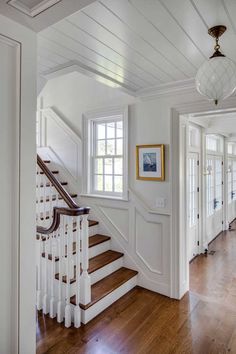 a white staircase with wood flooring and wooden handrails leading up to the second floor