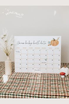 a calendar sitting on top of a table next to a vase filled with white flowers