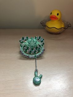 a green brooch with a rubber ducky in the background