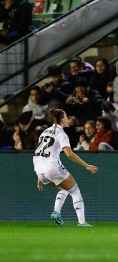 a female soccer player in action on the field during a game with fans watching from bleachers