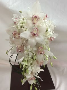 a bouquet of white flowers sitting on top of a black box with greenery in it