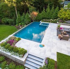 an aerial view of a pool surrounded by greenery and flowers, with stairs leading up to it