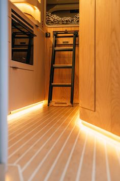 there is a ladder leading up to the bed in this small room with wood flooring