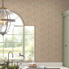 a kitchen with green cabinets and floral wallpaper on the walls next to a window