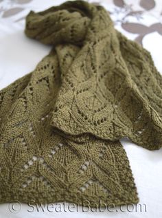 a green knitted scarf sitting on top of a bed