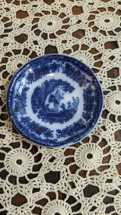 a blue and white plate sitting on top of a doily covered tablecloth with crocheted lace