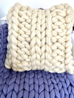 a knitted pillow sitting on top of a blue blanket