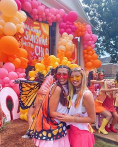 two girls are posing for the camera in front of balloons and streamers at a children's birthday party