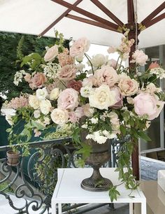 a vase filled with flowers sitting on top of a white table next to an umbrella