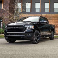 a black ram truck parked in front of a building