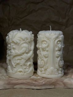 two white candles sitting next to each other