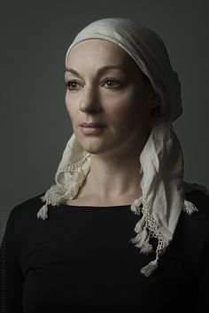 a woman with a white scarf on her head and black shirt, posing for the camera