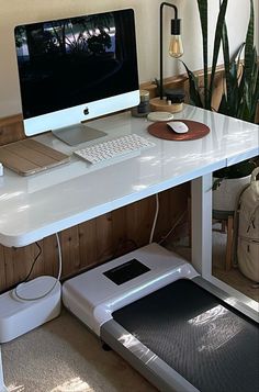 a white desk with a computer on it and a treadmill in front of it