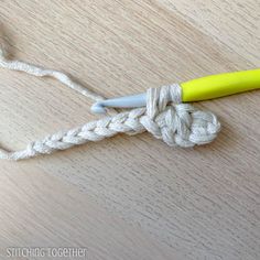 a yellow crochet hook is on top of a white rope