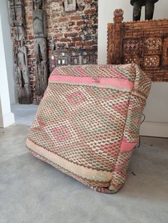 a large cushion sitting on the floor in front of a brick wall