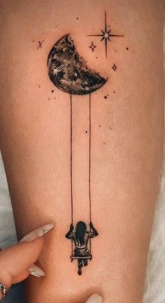 a woman's arm with a tattoo on it that has an image of the moon hanging