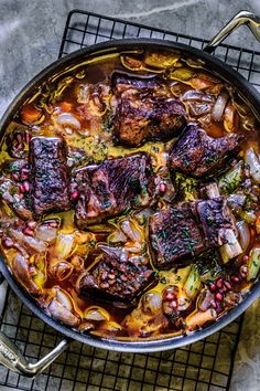 a pan filled with meat and vegetables on top of a wire rack