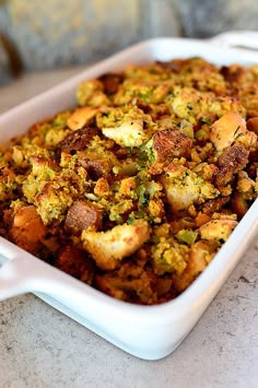 a white casserole dish filled with stuffing on top of a marble countertop